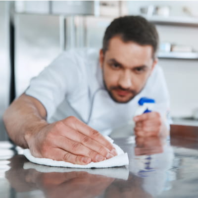 Worker Cleaning Kitchen Surface