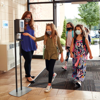 Children using PURELL Hand Sanitizer dispenser at entrance of K-12 school