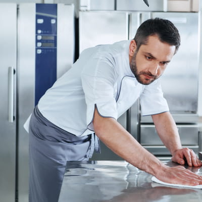 Man cleans food prep surface in commercial kitchen