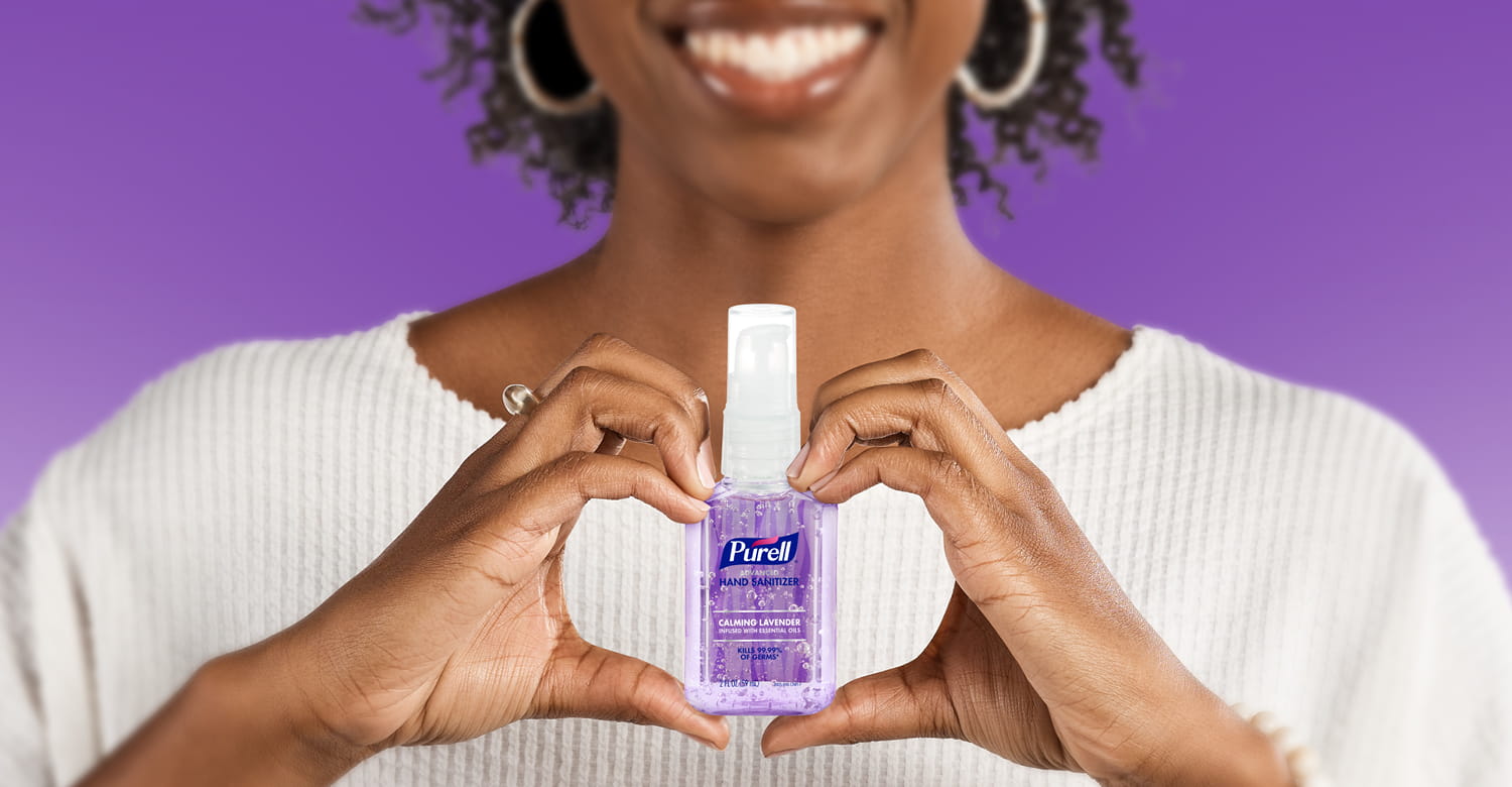 Person holding a PURELL portable calming lavender hand sanitizer bottle