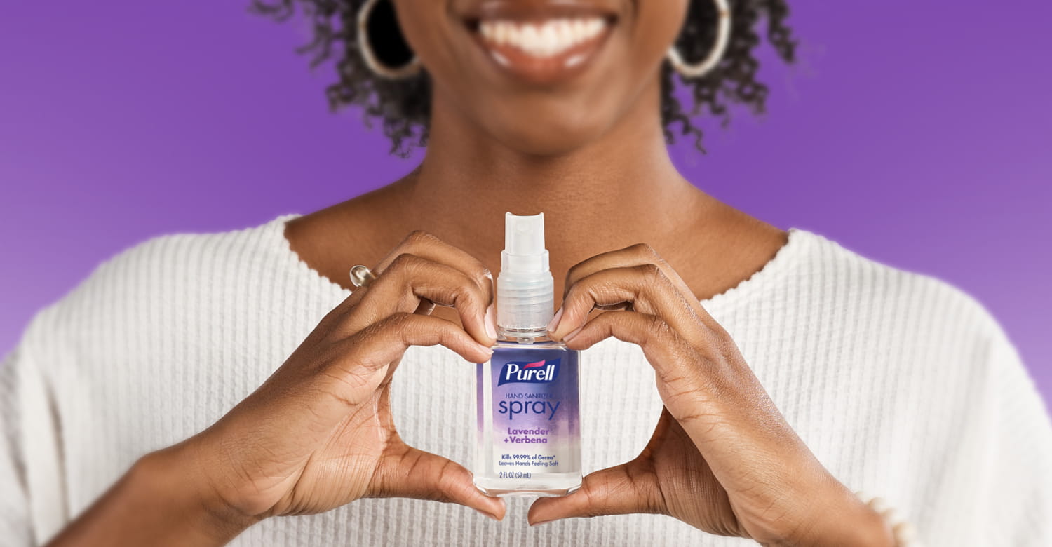 Person holding a PURELL Hand sanitizer spray bottle