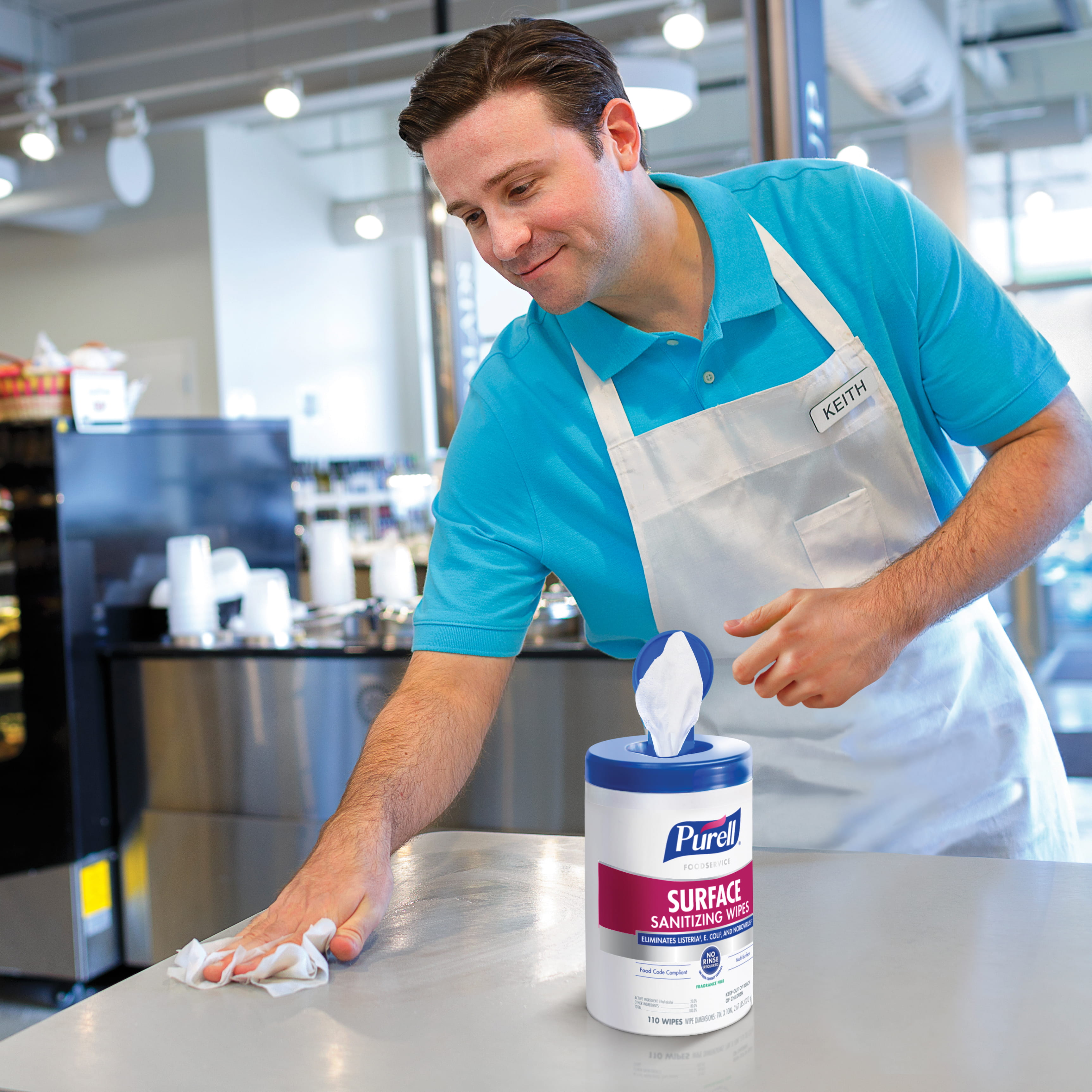 Grocery worker cleans surface with PURELL Professional Surface Disinfectant Wipes